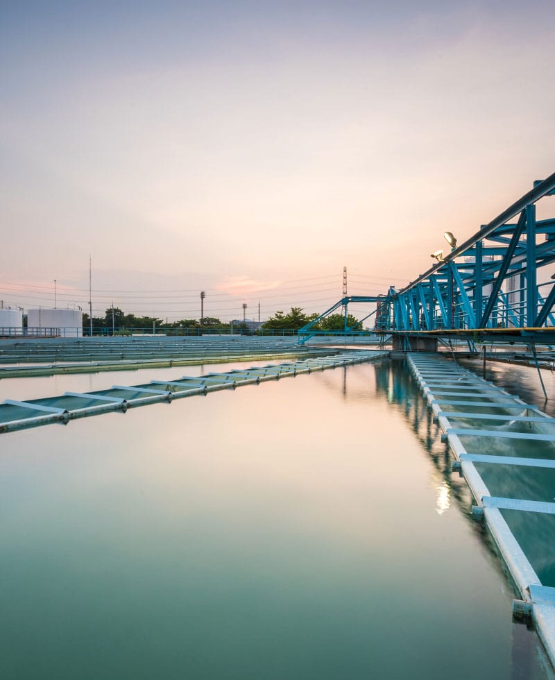 Große Wasseraufbereitungsanlage mit blauen Strukturen und ruhigem Wasser bei Sonnenuntergang