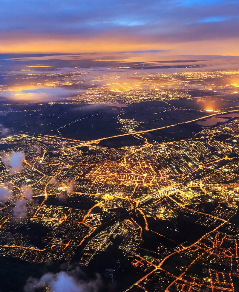 Nachtansicht aus der Vogelperspektive des beleuchteten Stromnetzes und Straßennetzes einer Stadt, die die Automatisierung im Bereich Smart Grid veranschaulicht.